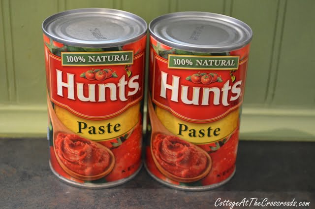 Two cans of 100% natural hunt's tomato paste.