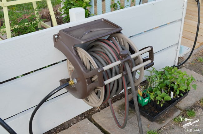 Hose reel mounted on wooden boards in the garden | cottage at the crossroads