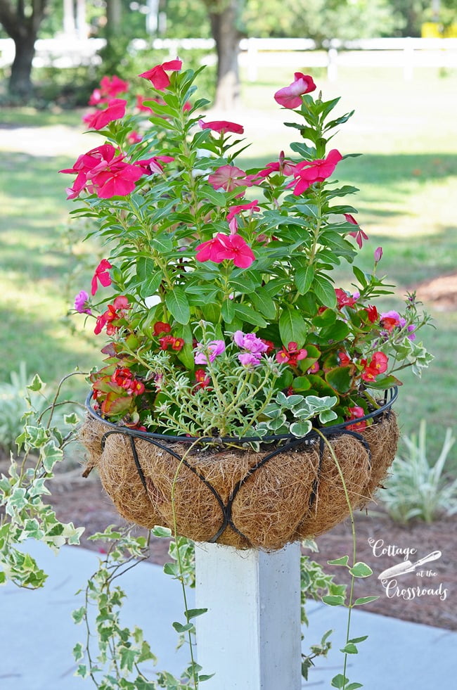 Flower baskets mounted on wooden posts | cottage at the crossroads