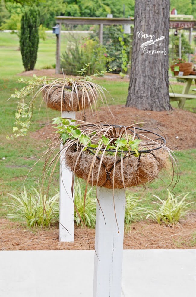 Flower baskets mounted on wooden posts | cottage at the crossroads