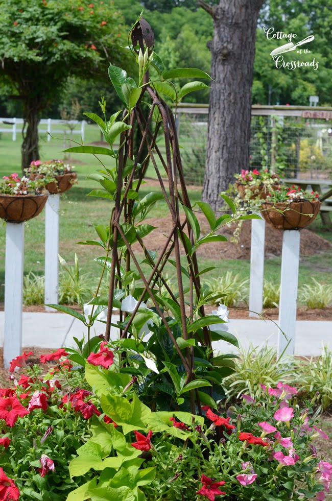 Flower baskets mounted on wooden posts | cottage at the crossroads