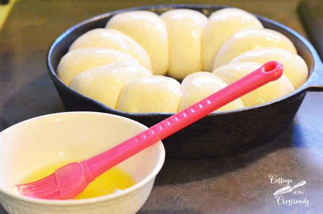 Spreading melted butter over thawed dinner rolls