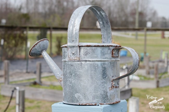 Watering can on top of wooden garden trellis | cottage at the crossroads