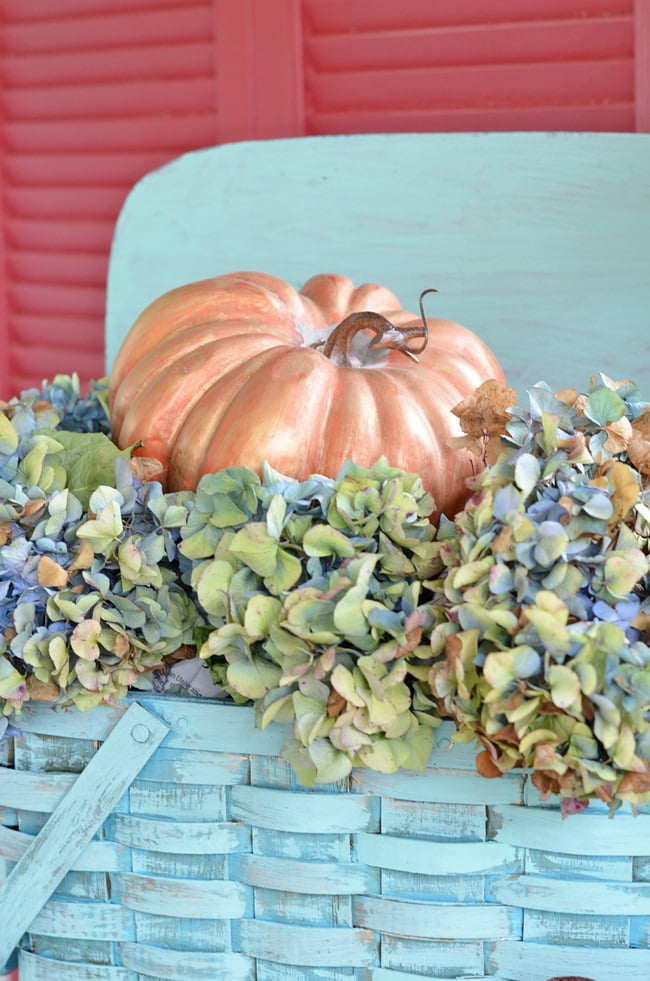 Dried hydrangeas in a vintage picnic basket on a fall porch