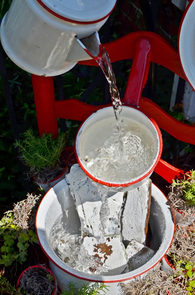 Painted rocks used to disguise tubing in an enamelware chair fountain