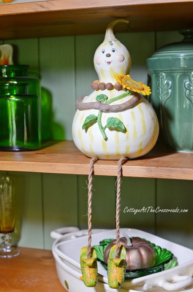 Gourd lady on a fall decorated cupboard