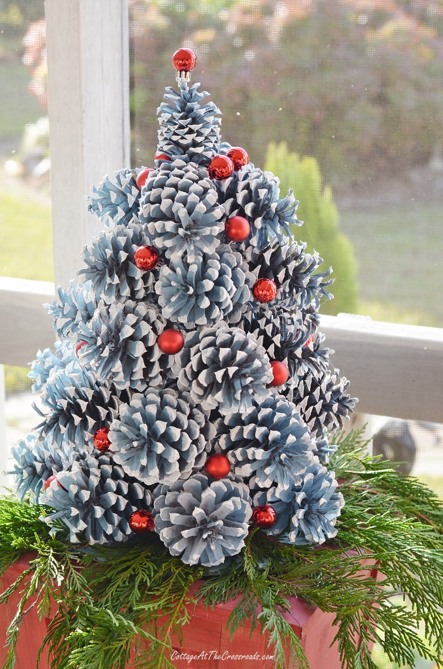 Red miniature christmas ornaments used on a pine cone christmas tree