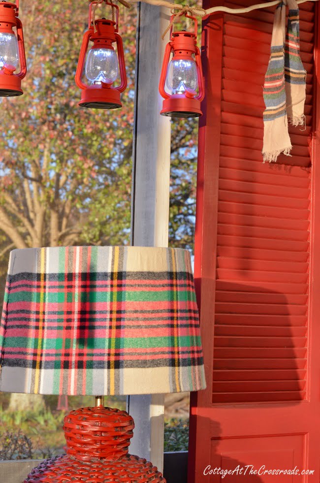 Red lanterns and a plaid lampshade on a christmas front porch