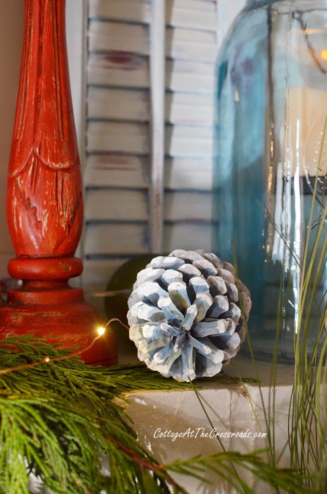 Blue painted pine cone on a traditional christmas mantel