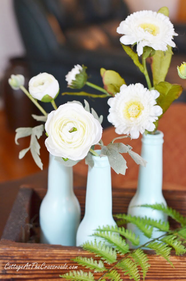 Faux flowers in aqua bottles