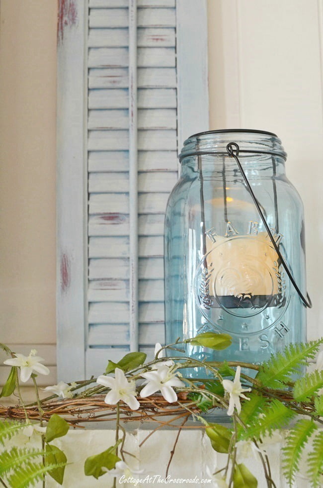 Old wooden shutter painted blue with a blue mason jar