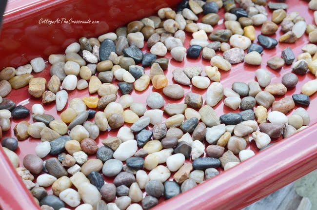 Layer of pebbles in the bottom of a red wagon
