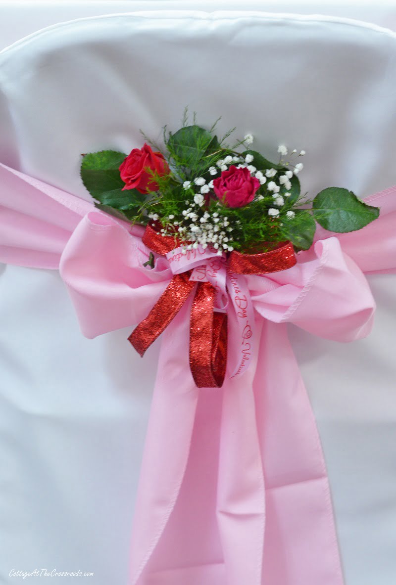 Pink and red floral decoration on the back of chair covers at a valentine's day tablescape