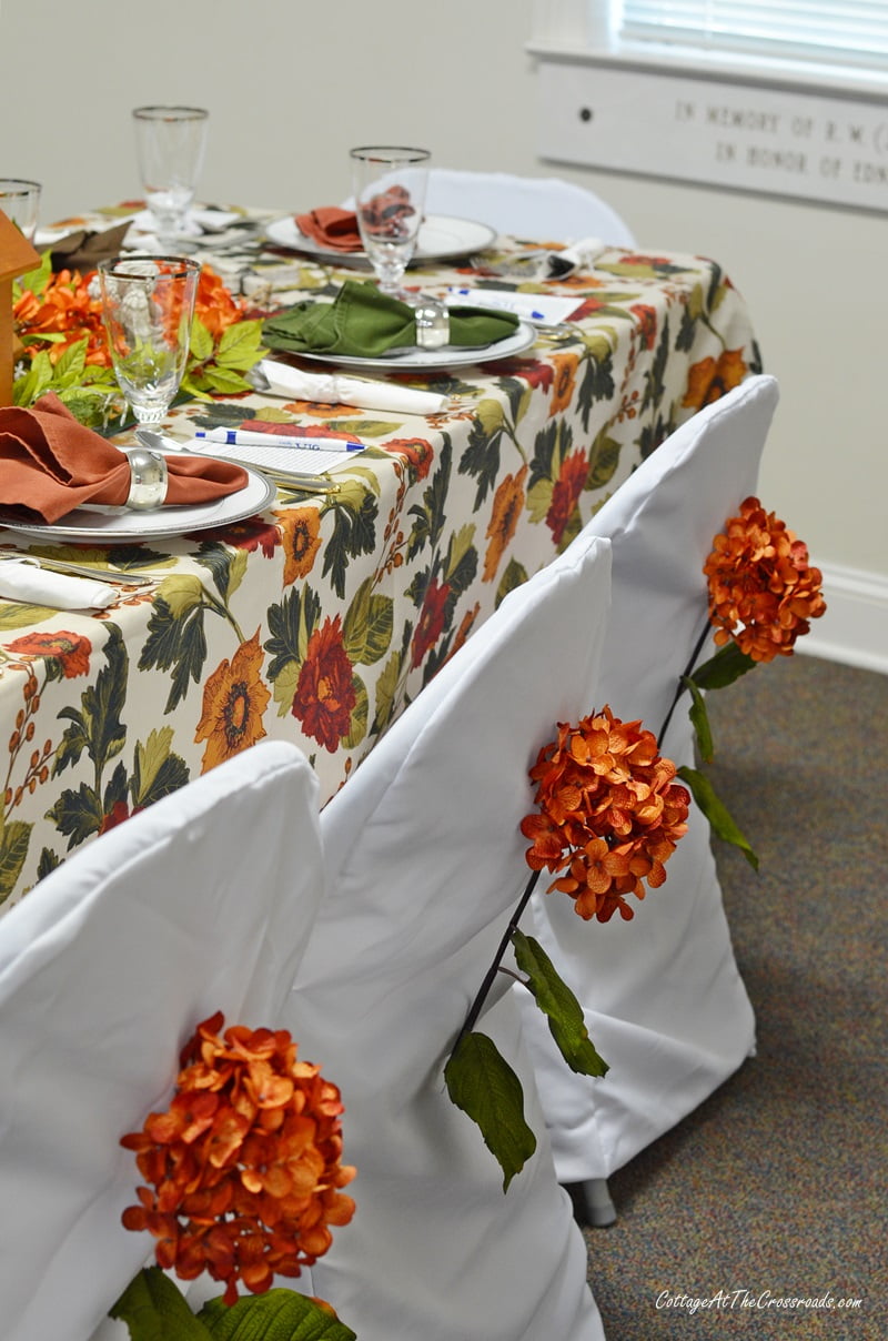 Orange hydrangeas on chair backs at tablesetting fundraiser