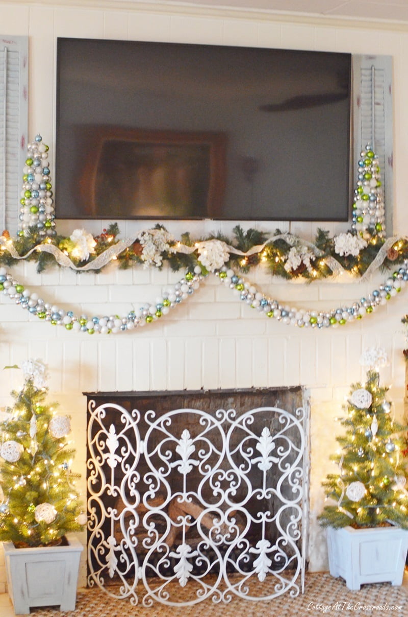 Trees in blue planters at the base of a christmas mantel