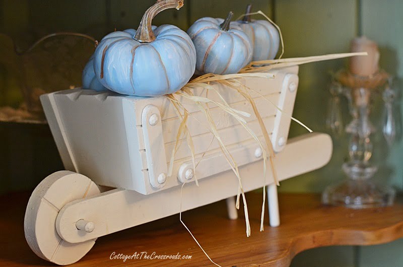 White wheelbarrow filled with blue pumpkins