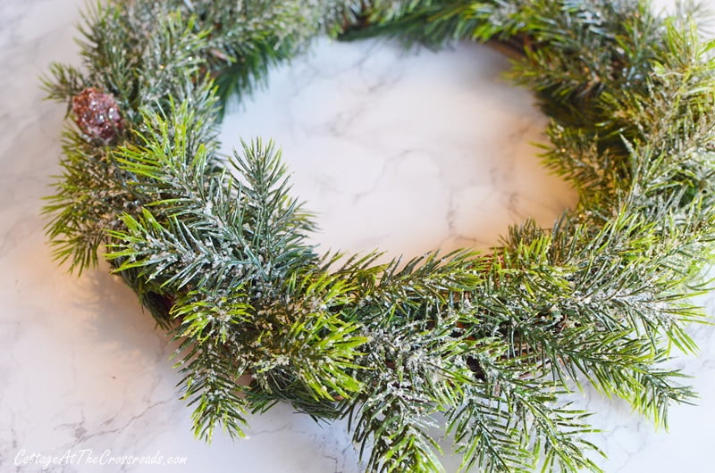 Frosted greenery attached to a small grapevine wreath