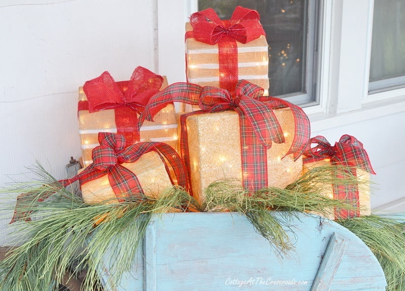 Lighted gift boxes in a vintage wheelbarrow on a christmas front porch