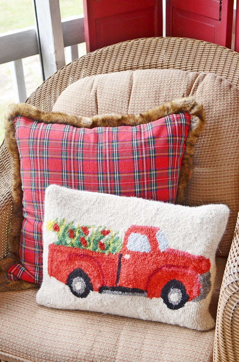 Red truck and plaid pillows in a chair on a christmas front porch