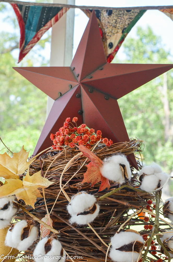 Metal star on top of a twig tree on a fall decorated porch
