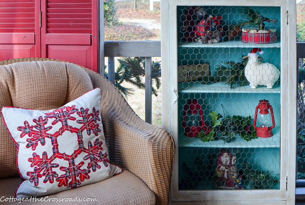 Aqua jelly cupboard and a wicker chair on a christmas front porch