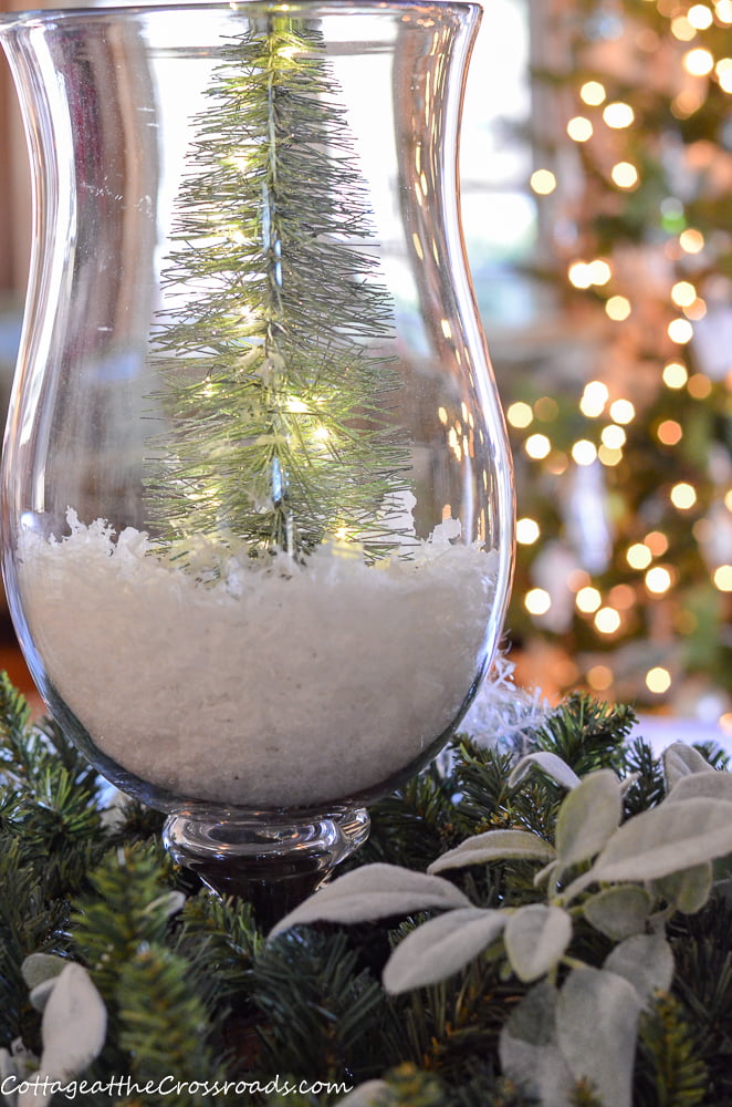 Lighted tree in glass candle holder surrounded by a wreath