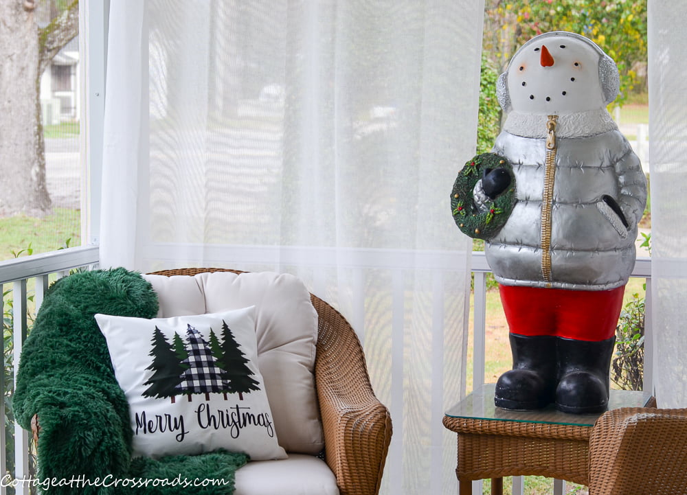 Christmas pillow and snowman on a christmas front porch
