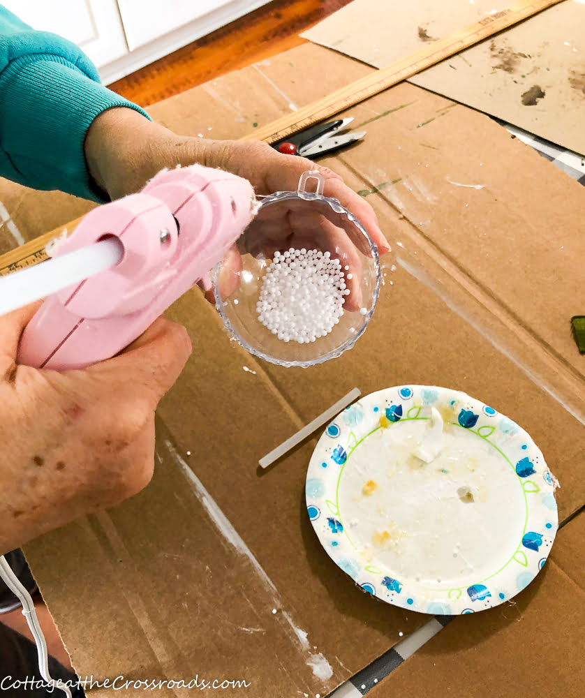 Adding hot glue around edge of plastic sphere ornament