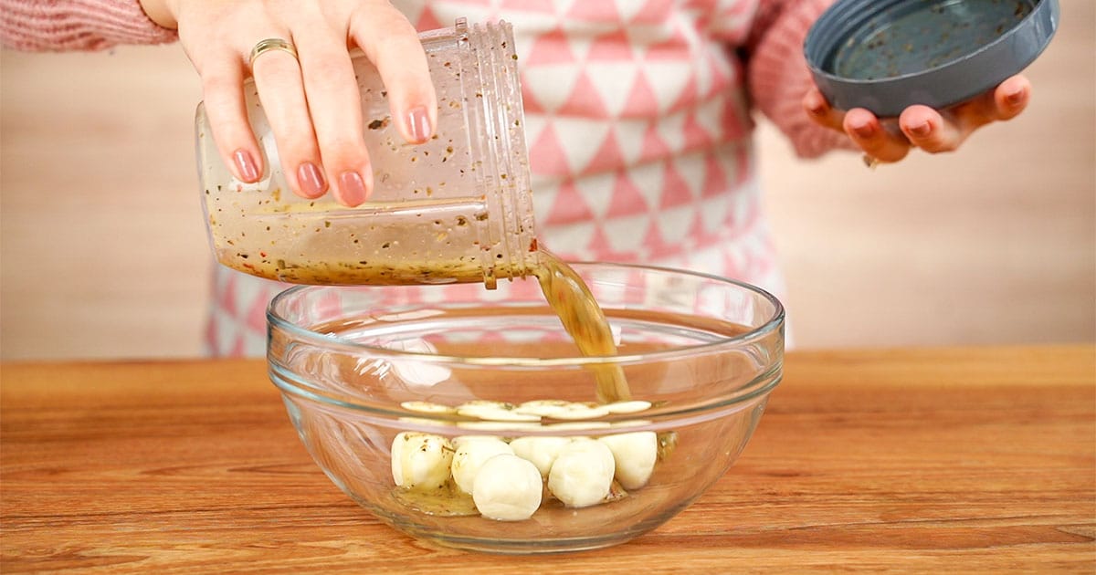 Marinade being poured over mozzarella balls to make marinated mozzarella balls
