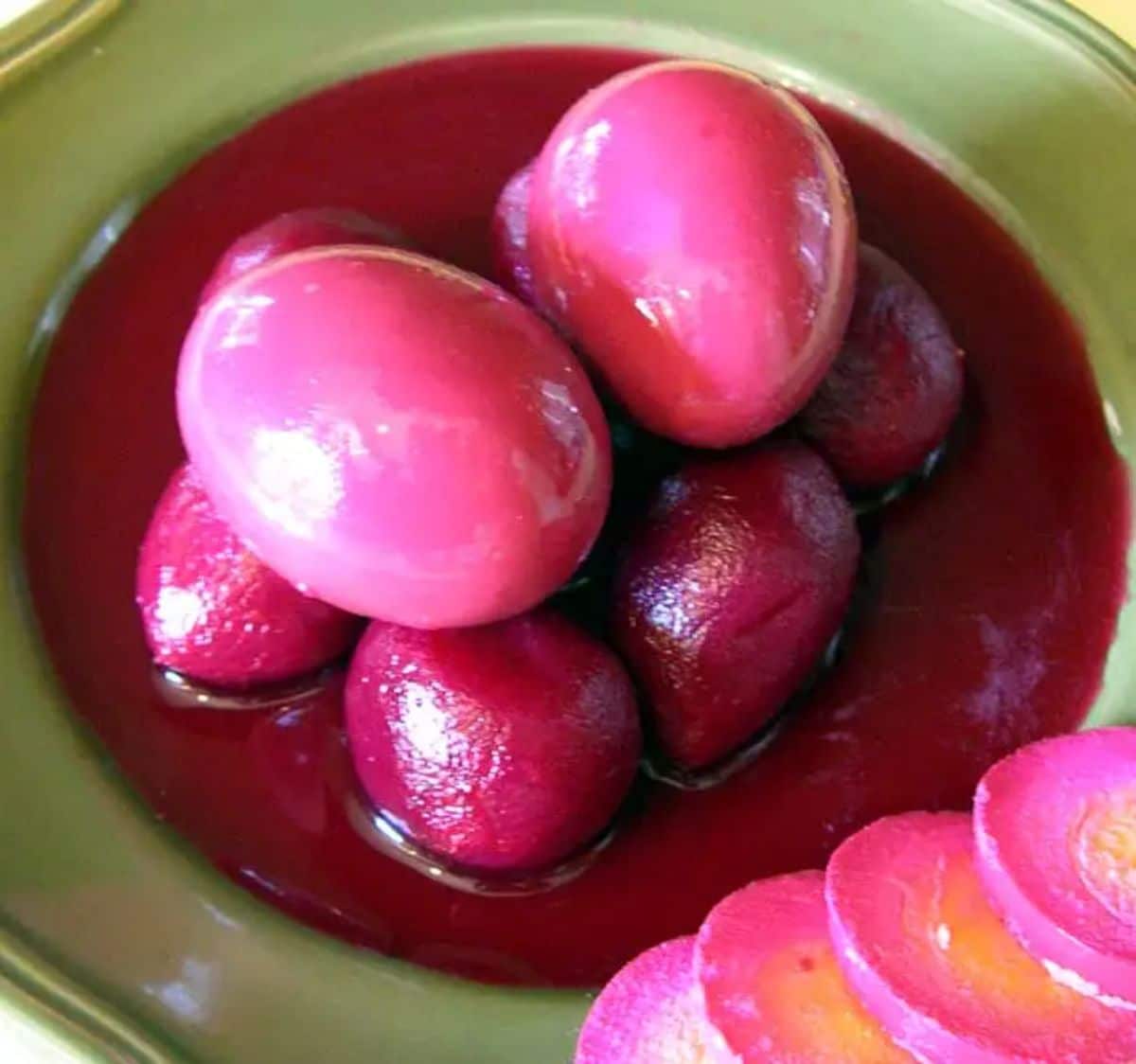 Pickled eggs and red beets on a green plate.