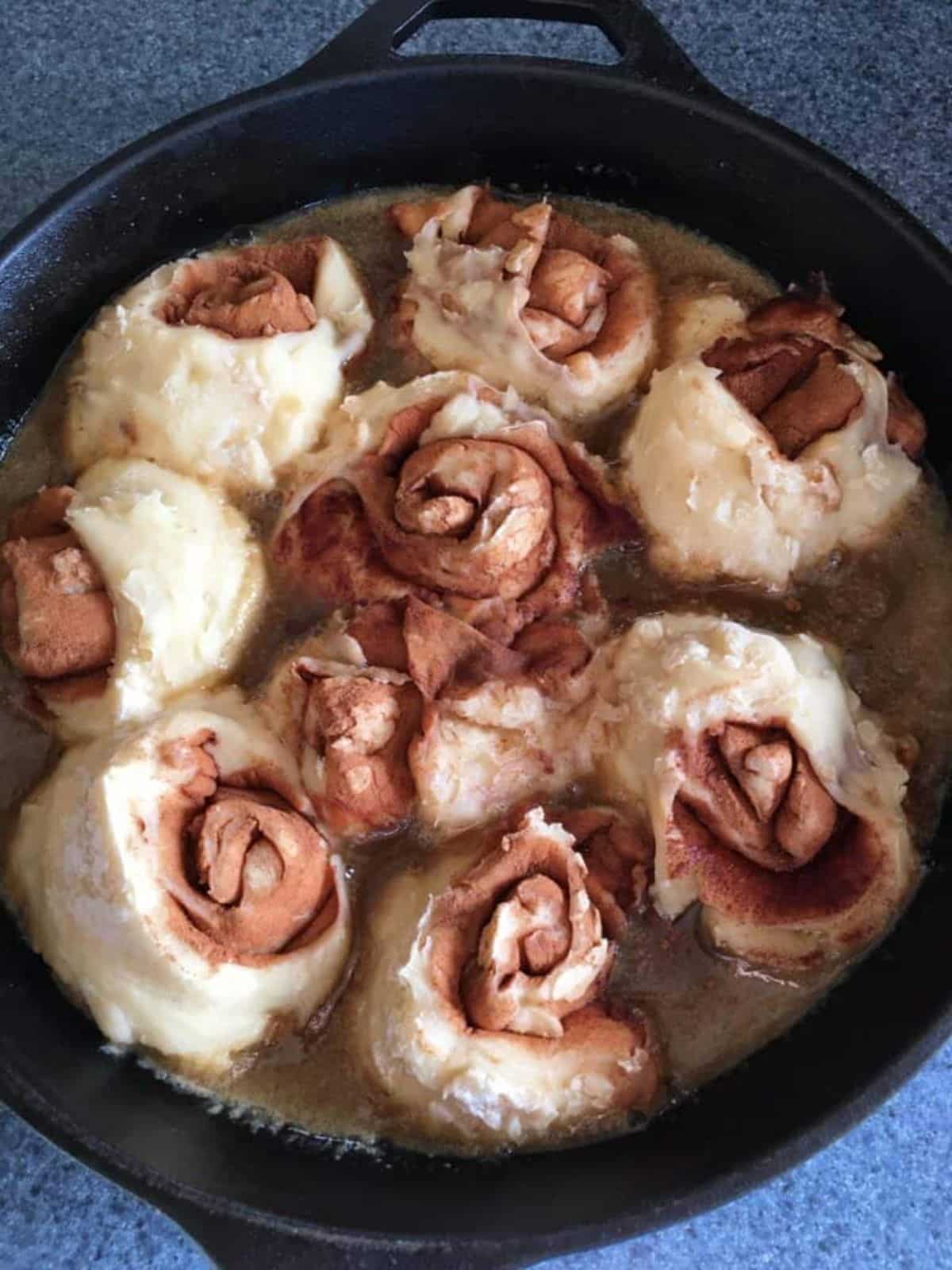 Sourdough caramel rolls in a black skillet.