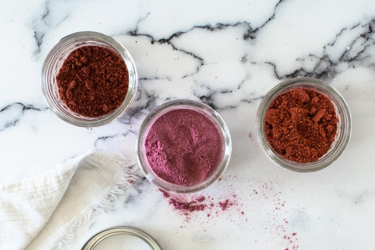 Three different fruit powders in glass jars.