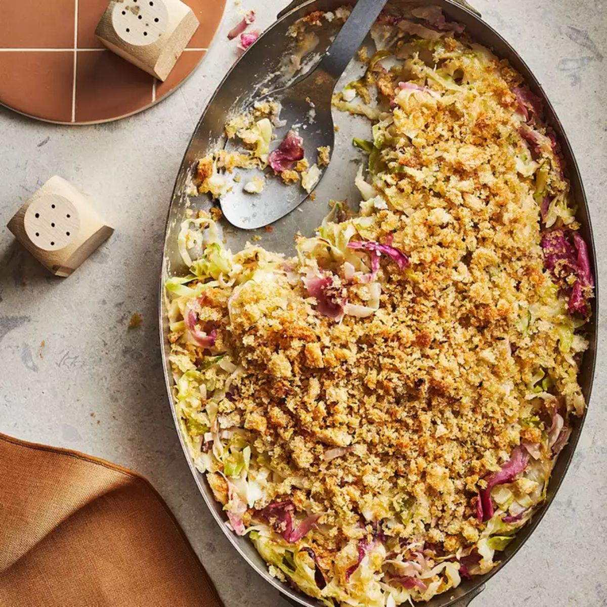 Creamed cabbage & sauerkraut with rye breadcrumbs in a casserole with a spoon.