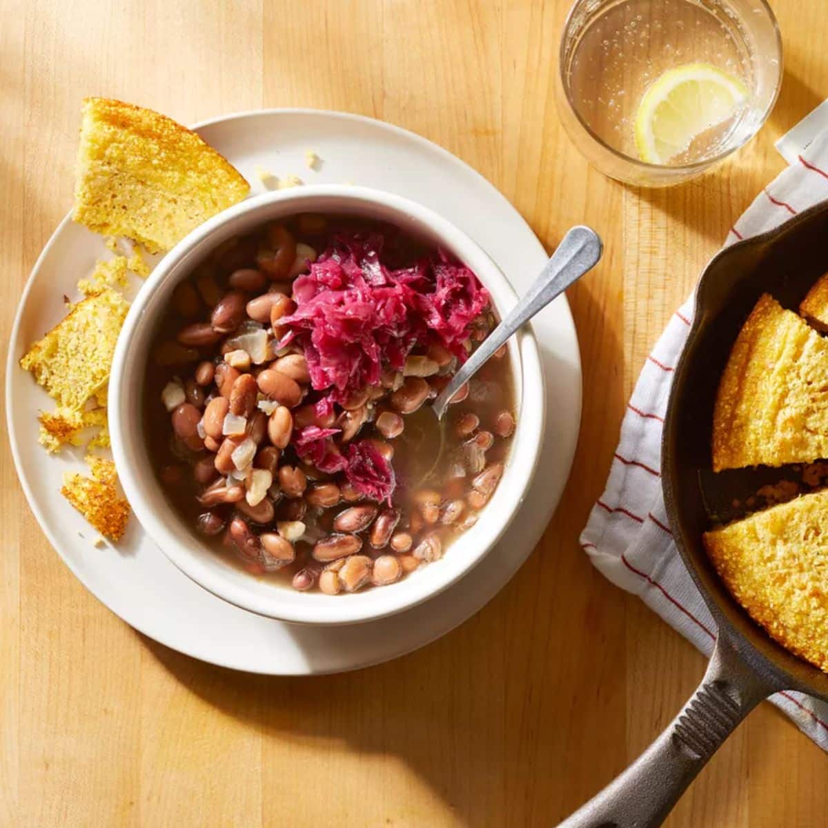 Soup beans with cornbread and sauerkraut in a white bowl.