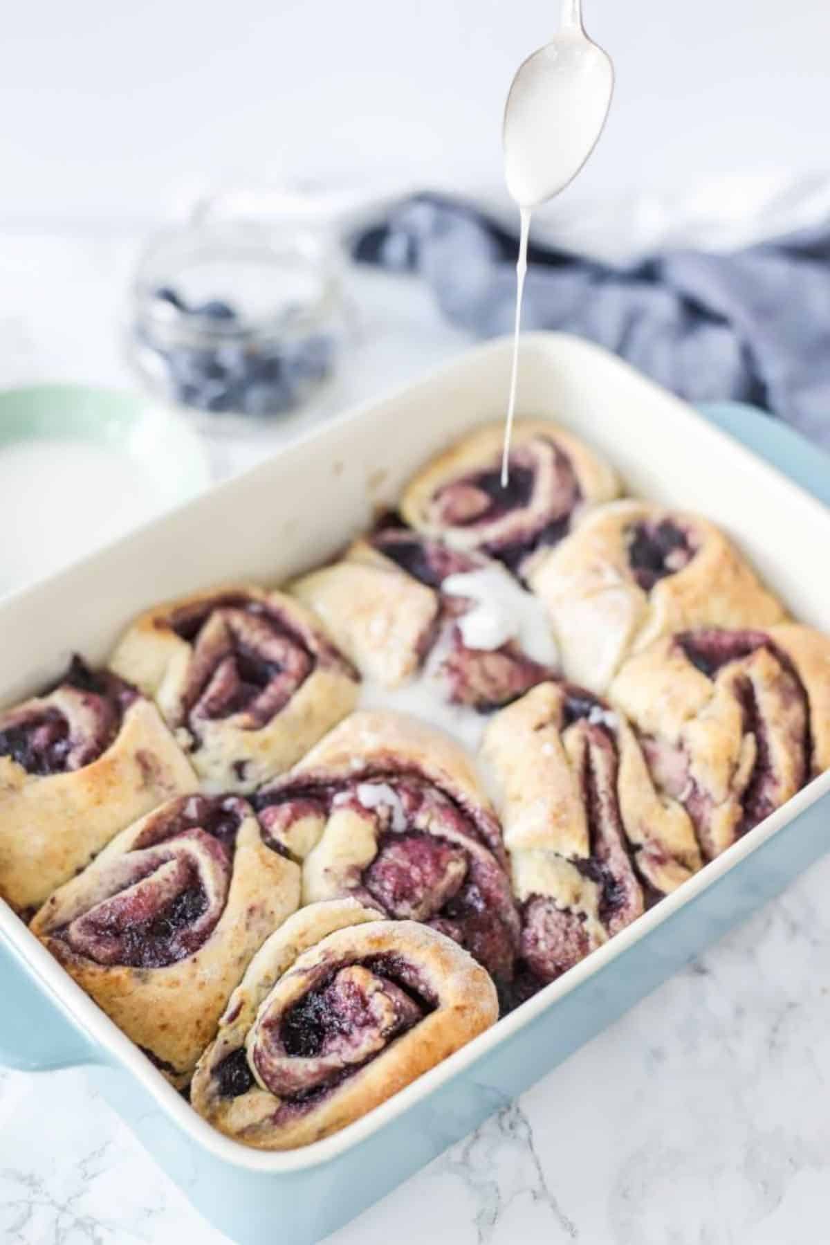 Blueberry sourdough sweet rolls in a white casserole.