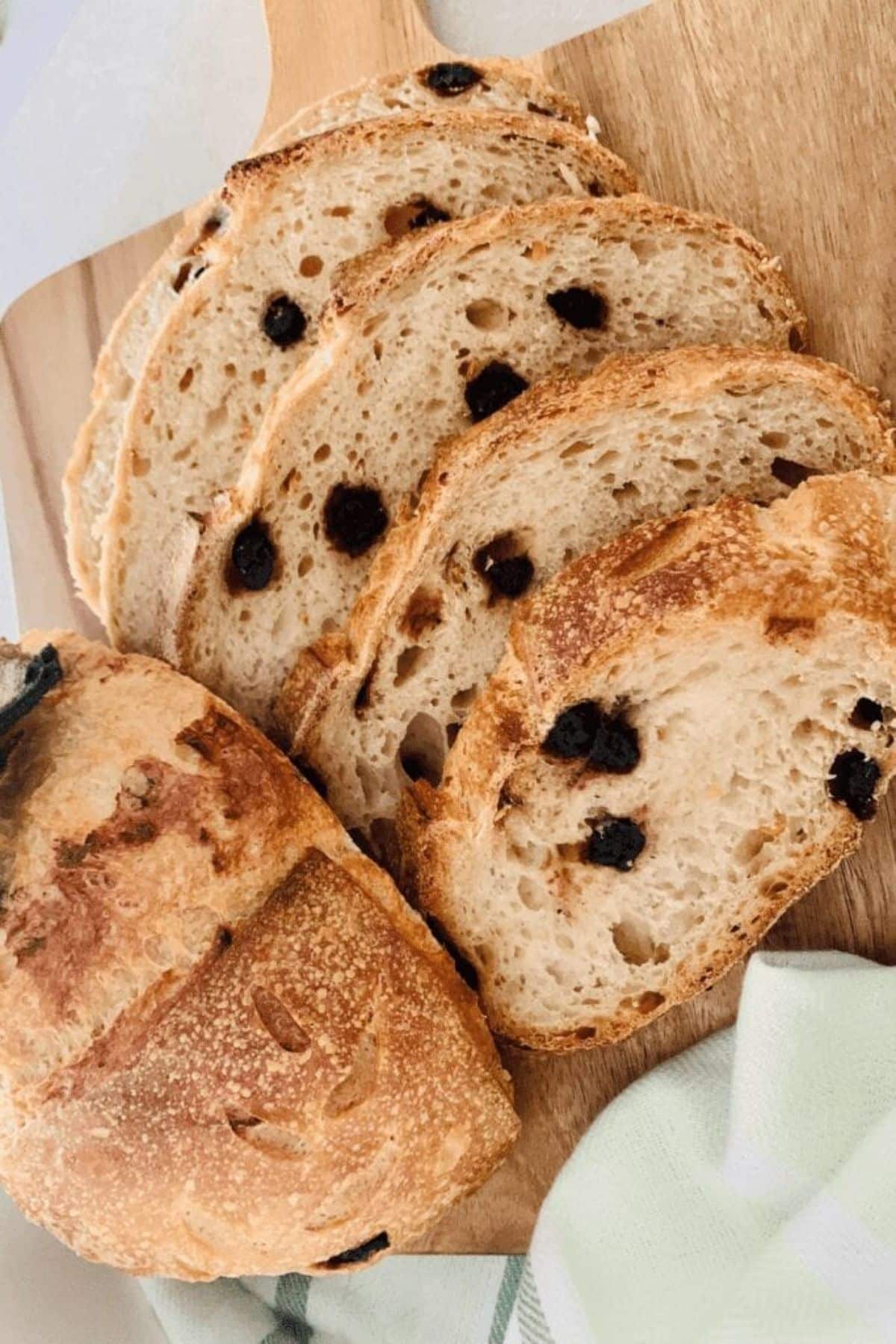 Slices of maple blueberry & sweet lemon zest sourdough bread on a wooden cutting board.