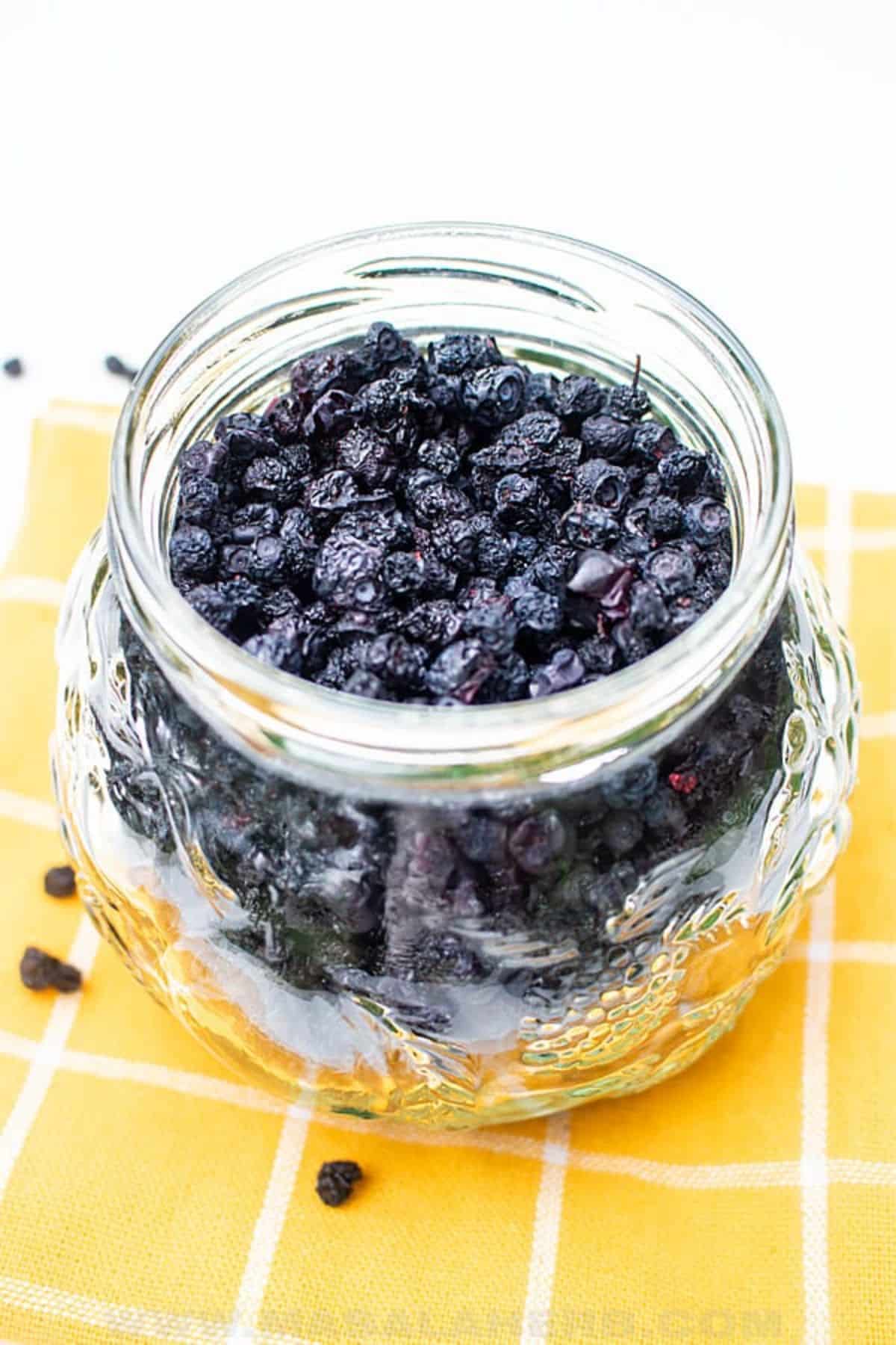A glass jar of dehydrated blueberries.