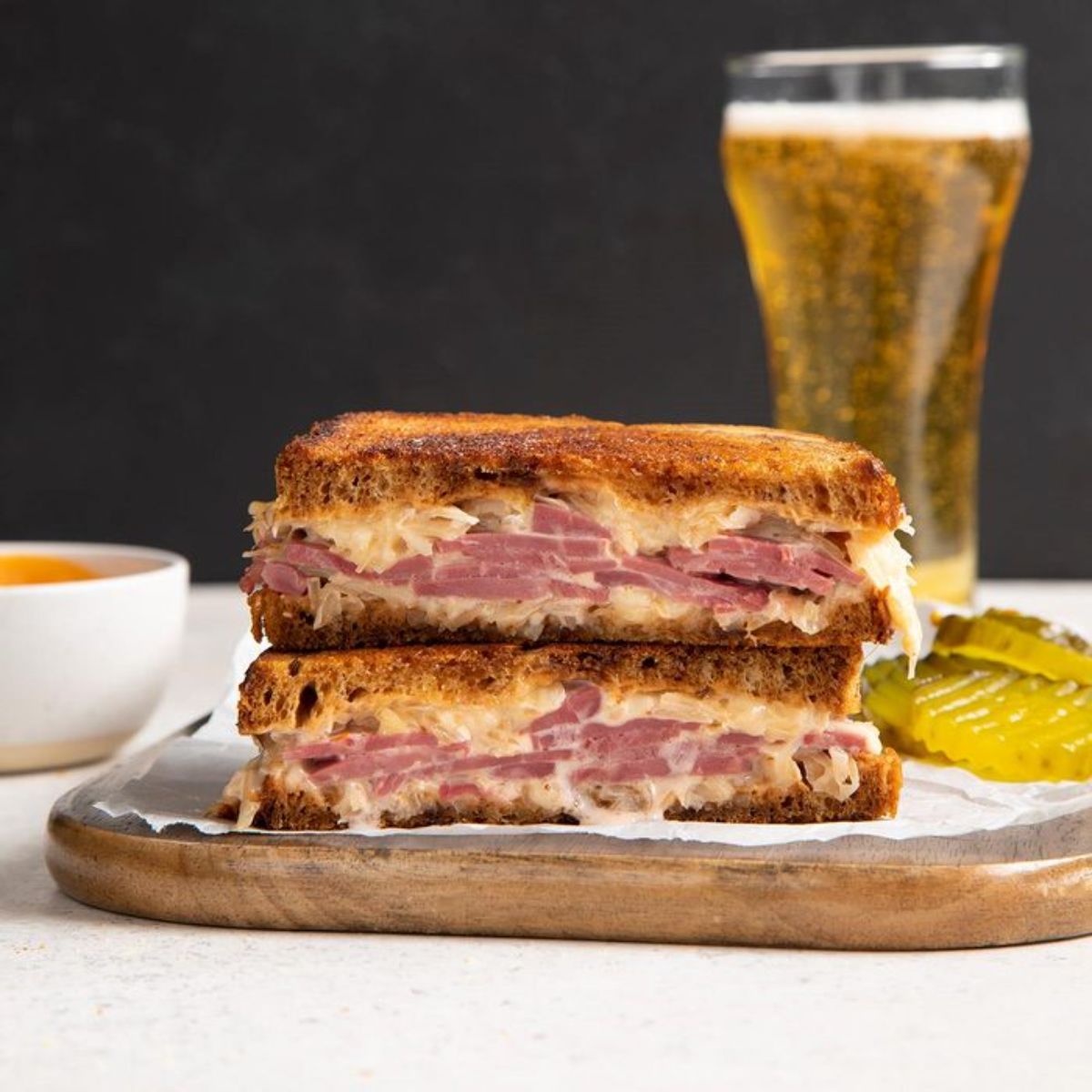 Two corned beef sandwiches on a wooden cutting board.