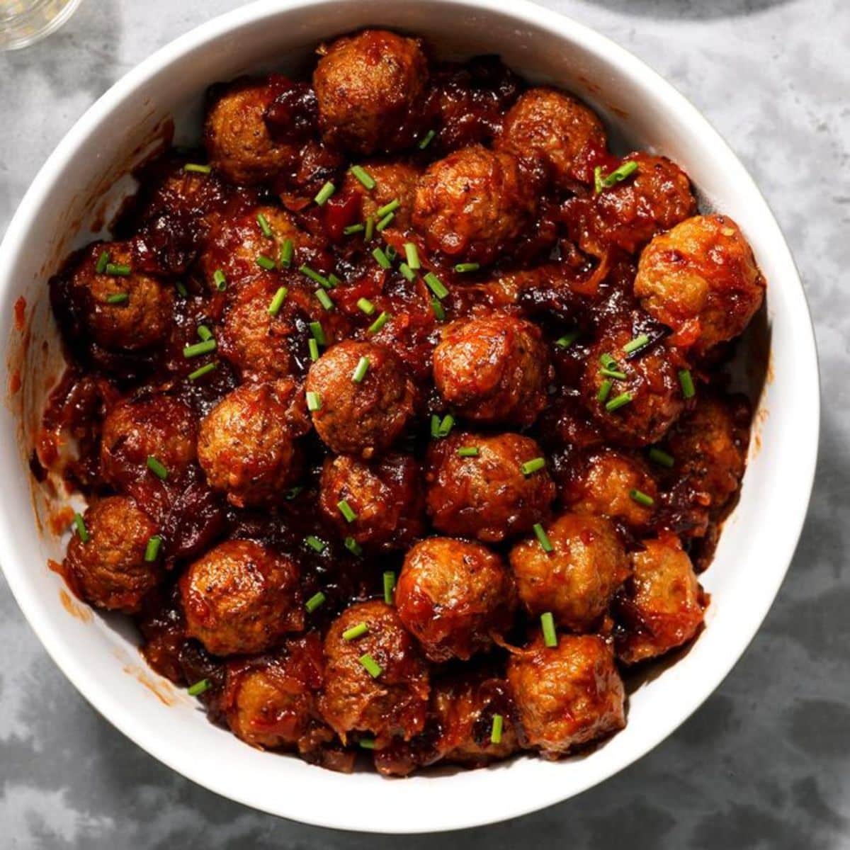 Cranberry sauerkraut meatballs in a white bowl.