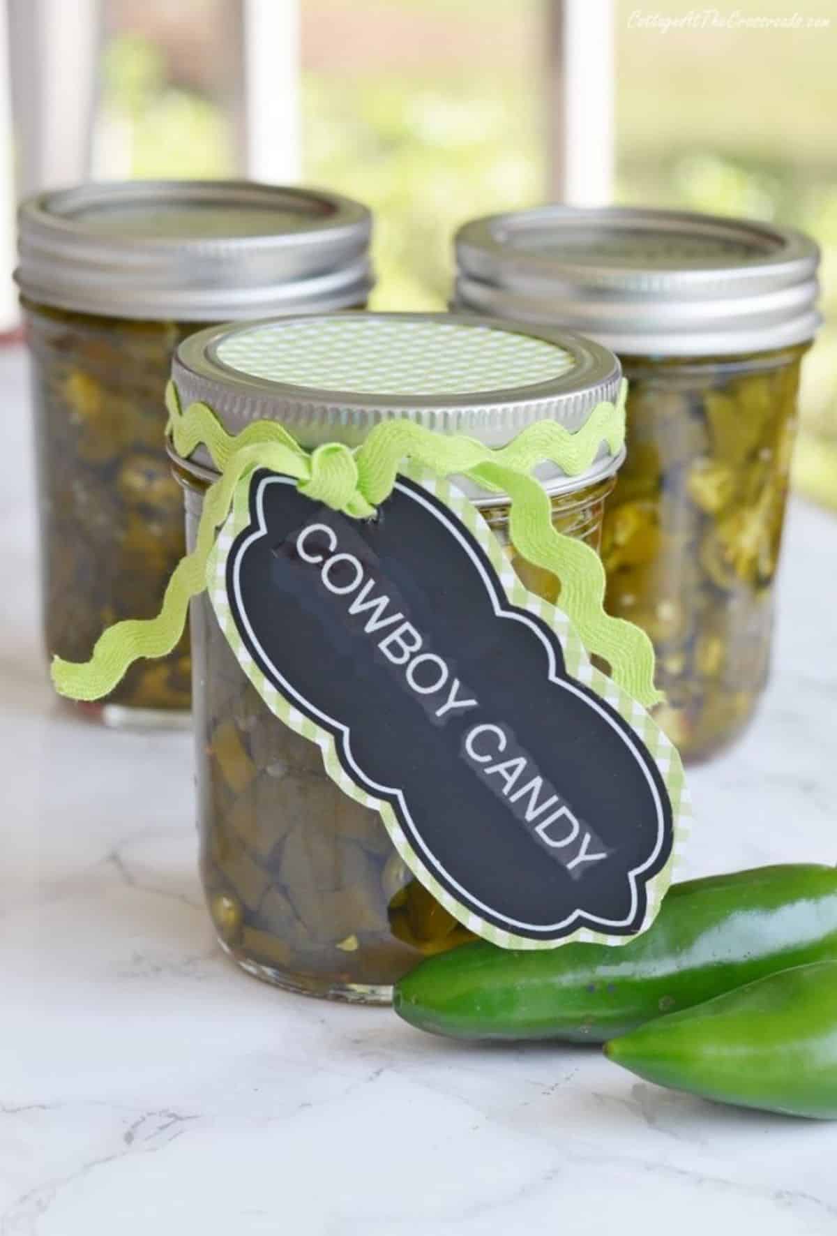 Candied jalapenos in three glass jars.