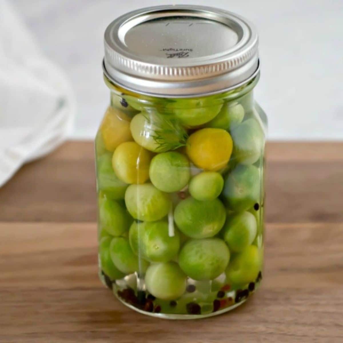 Pickled green tomatoes in a glass jar.
