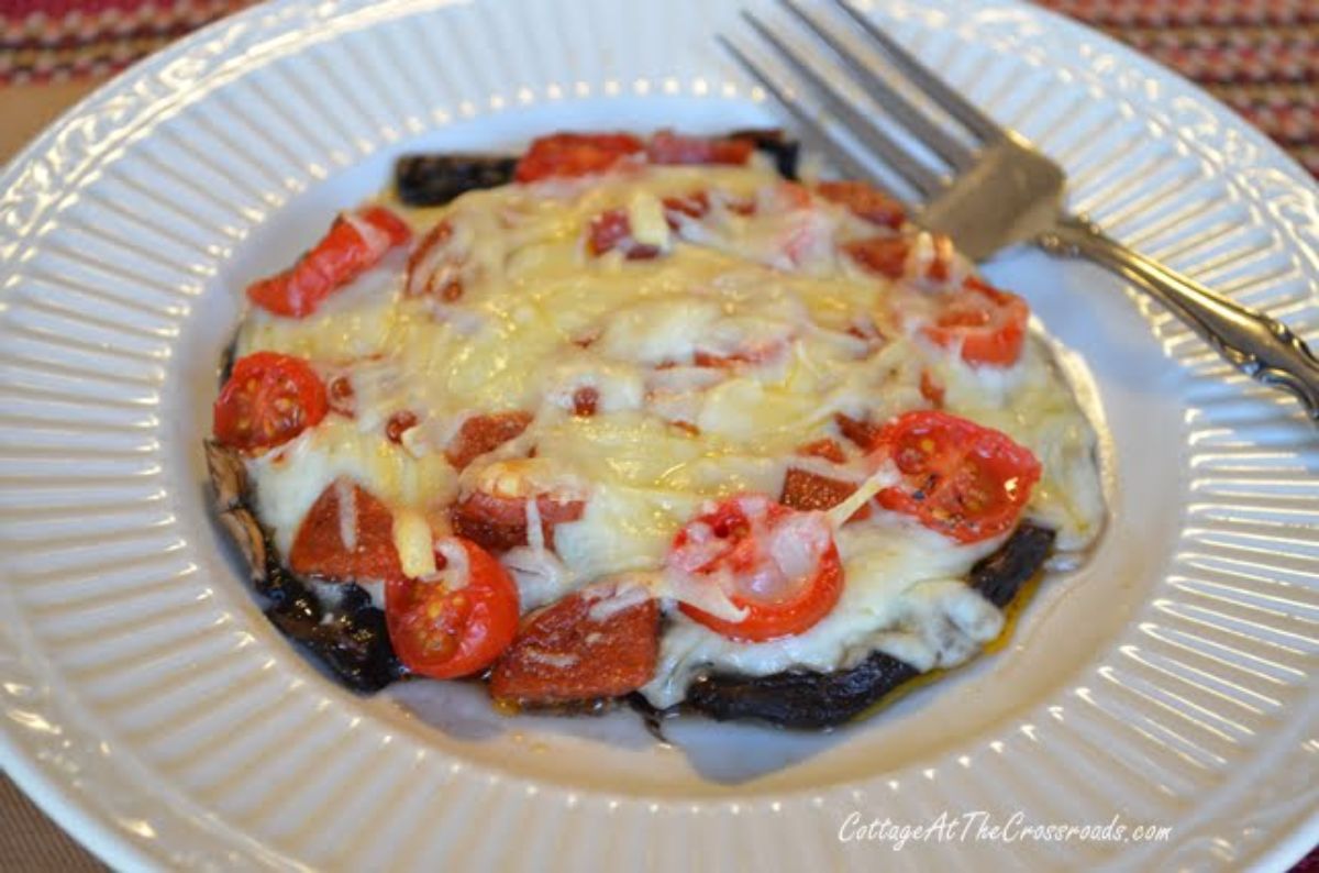 Delicious portabella pizza on a white plate with a fork.