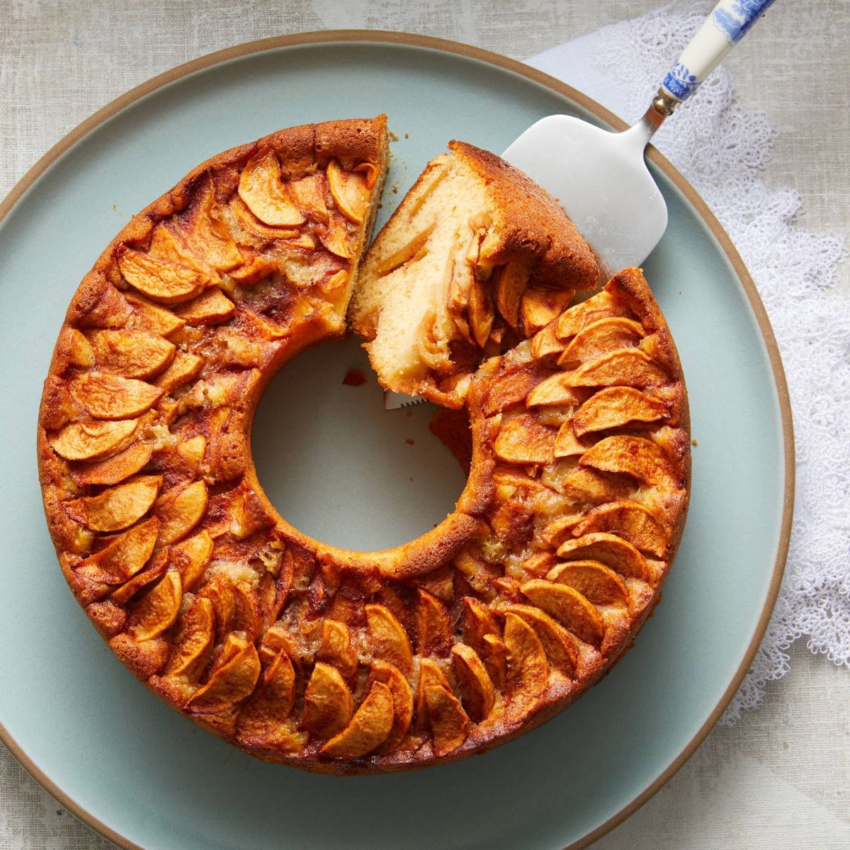 Classic jewish apple cake on a blue tray with a spatula.