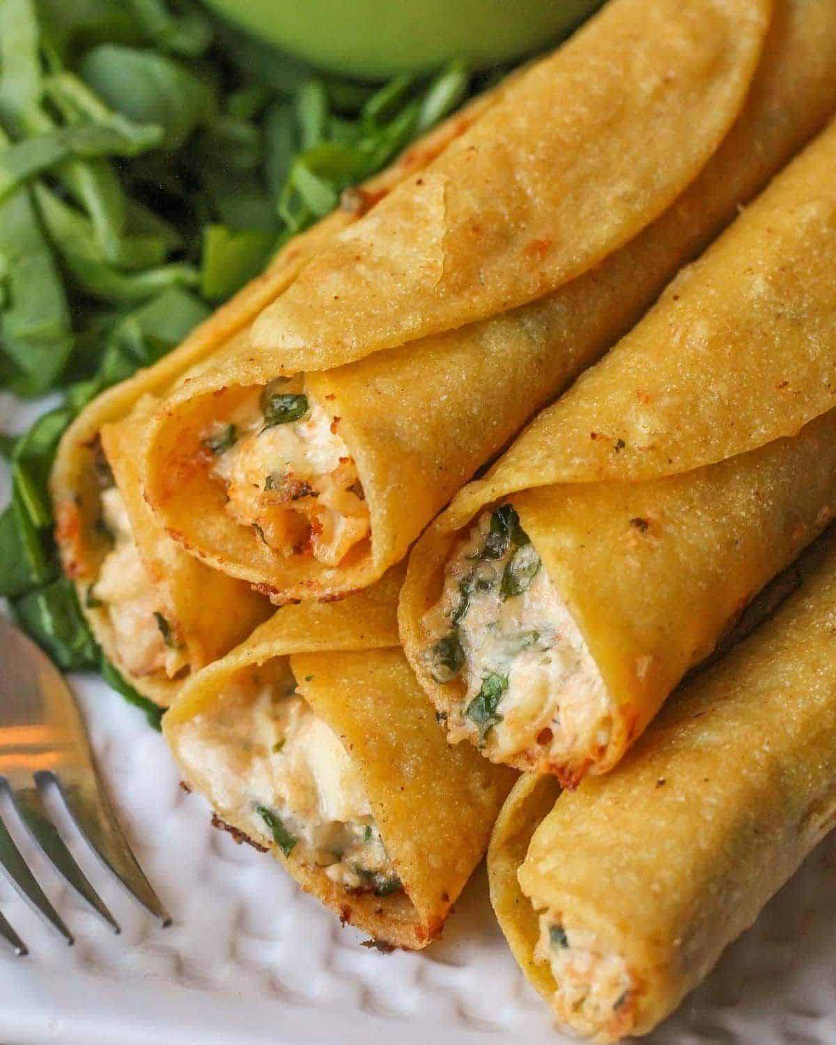 Crunchy cream cheese and chicken taquitos on a white plate.