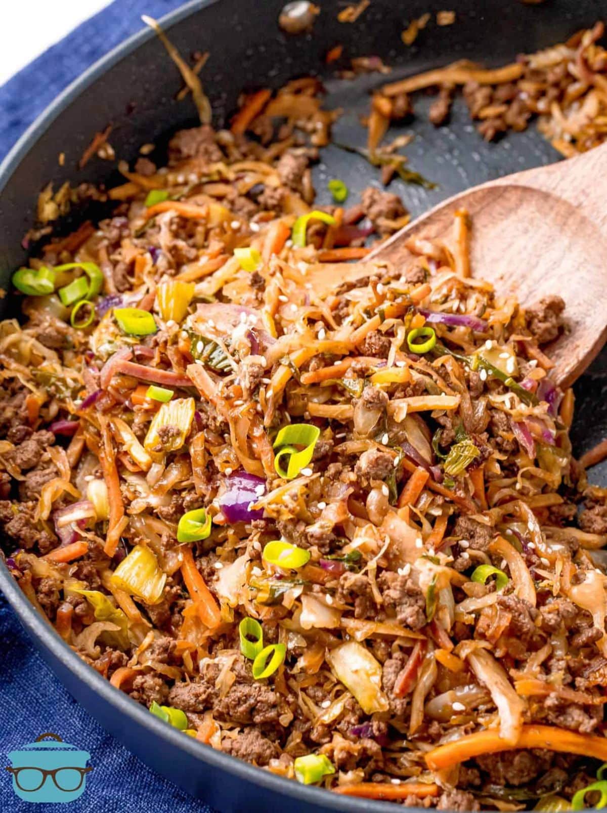 Beef egg roll in a black skillet with a wooden spatula.