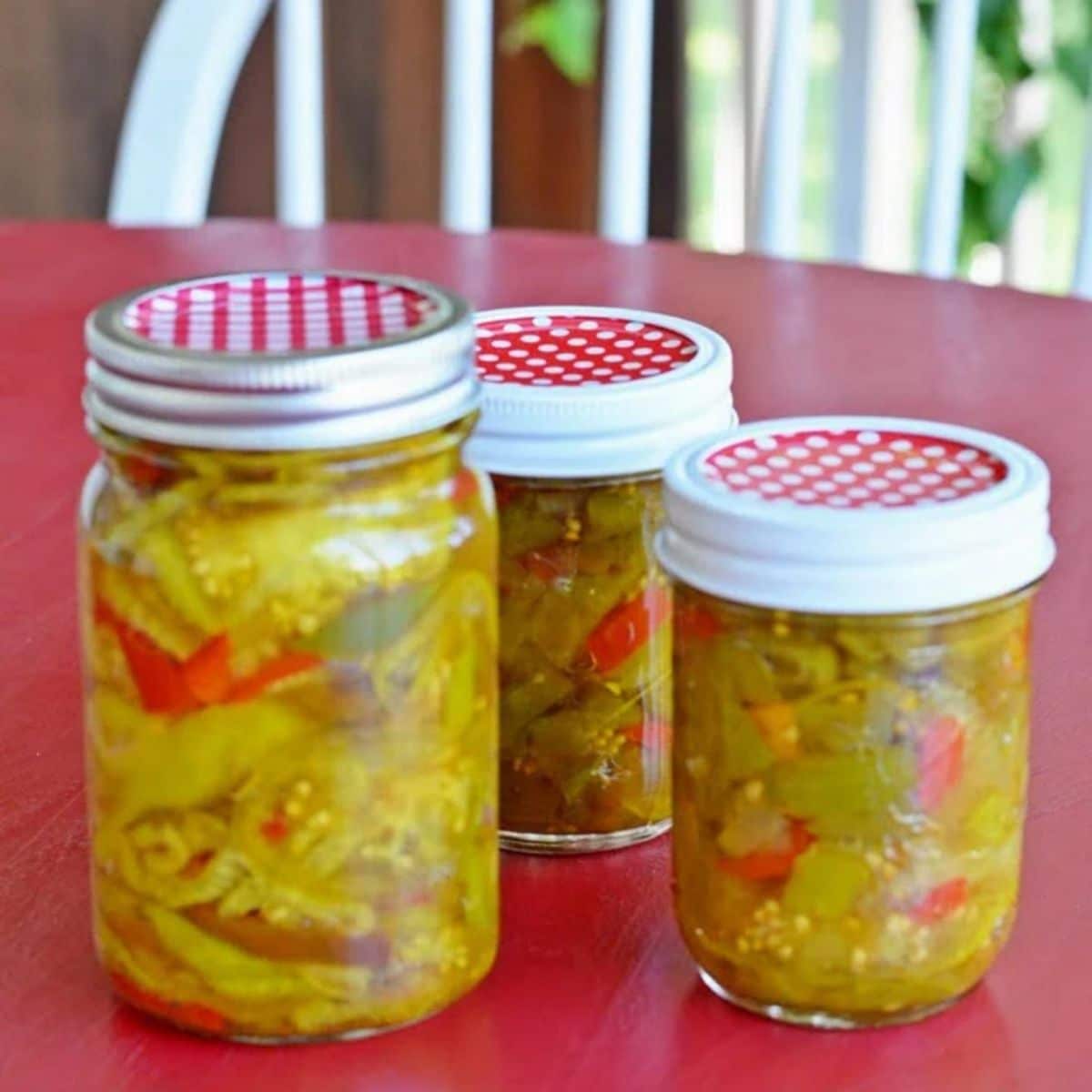 Green tomato relish in three glass jars.