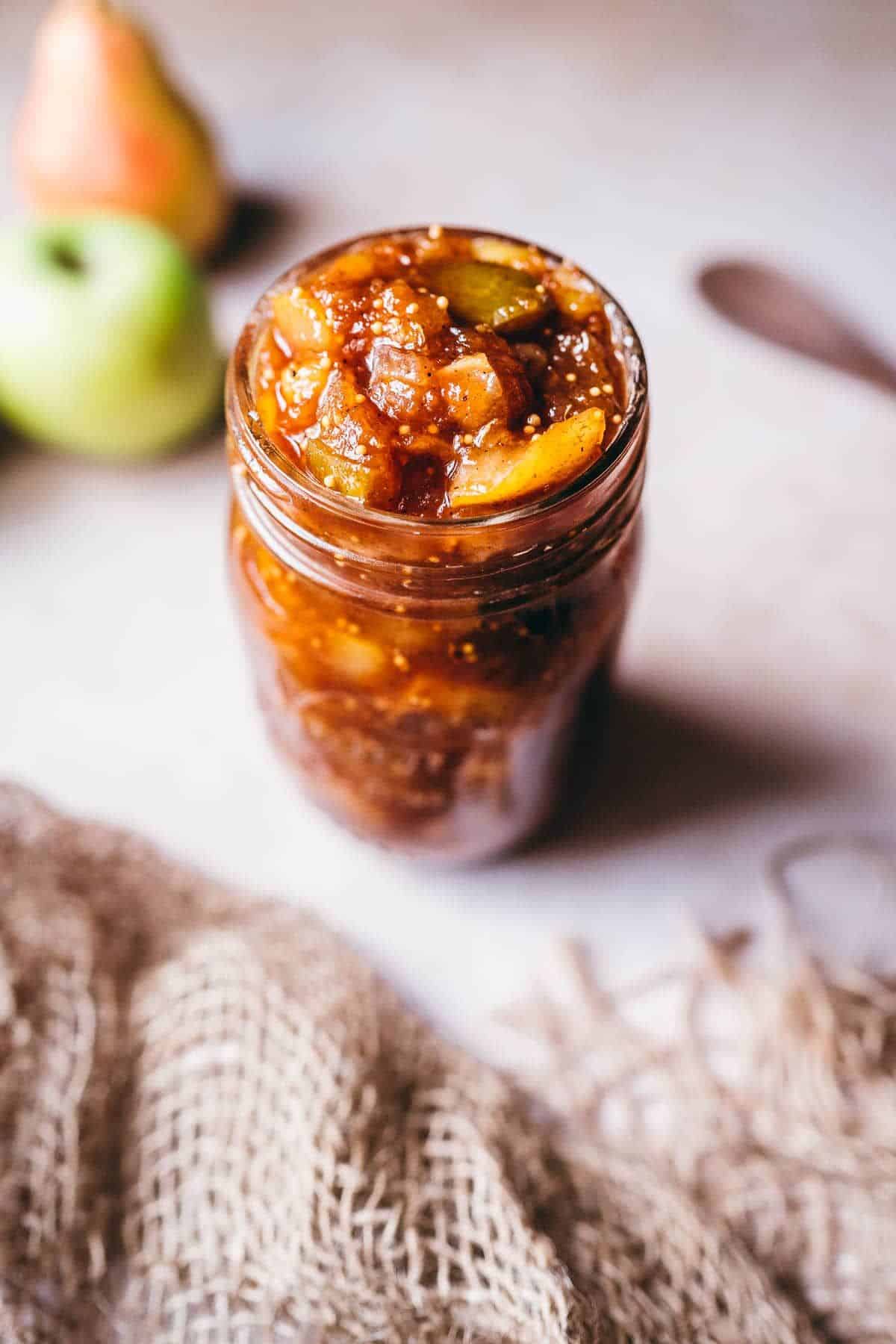 Delicious apple and pear chutney in a glass jar.