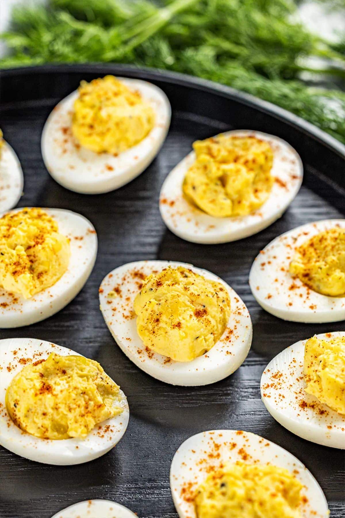 Delicious stuffed eggs on a black plate.