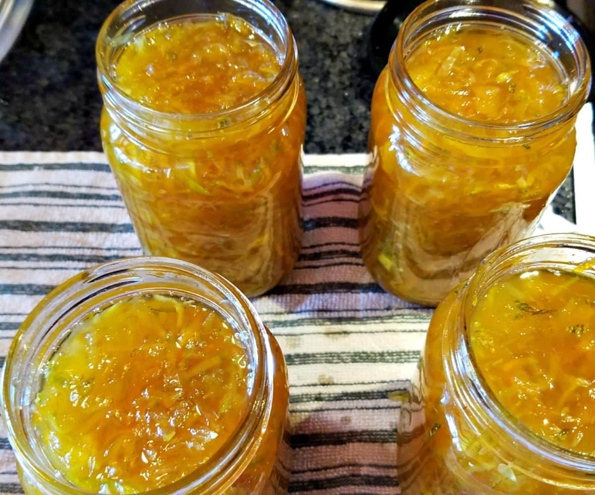 Zucchini carrot ginger marmalade in four glass jars.