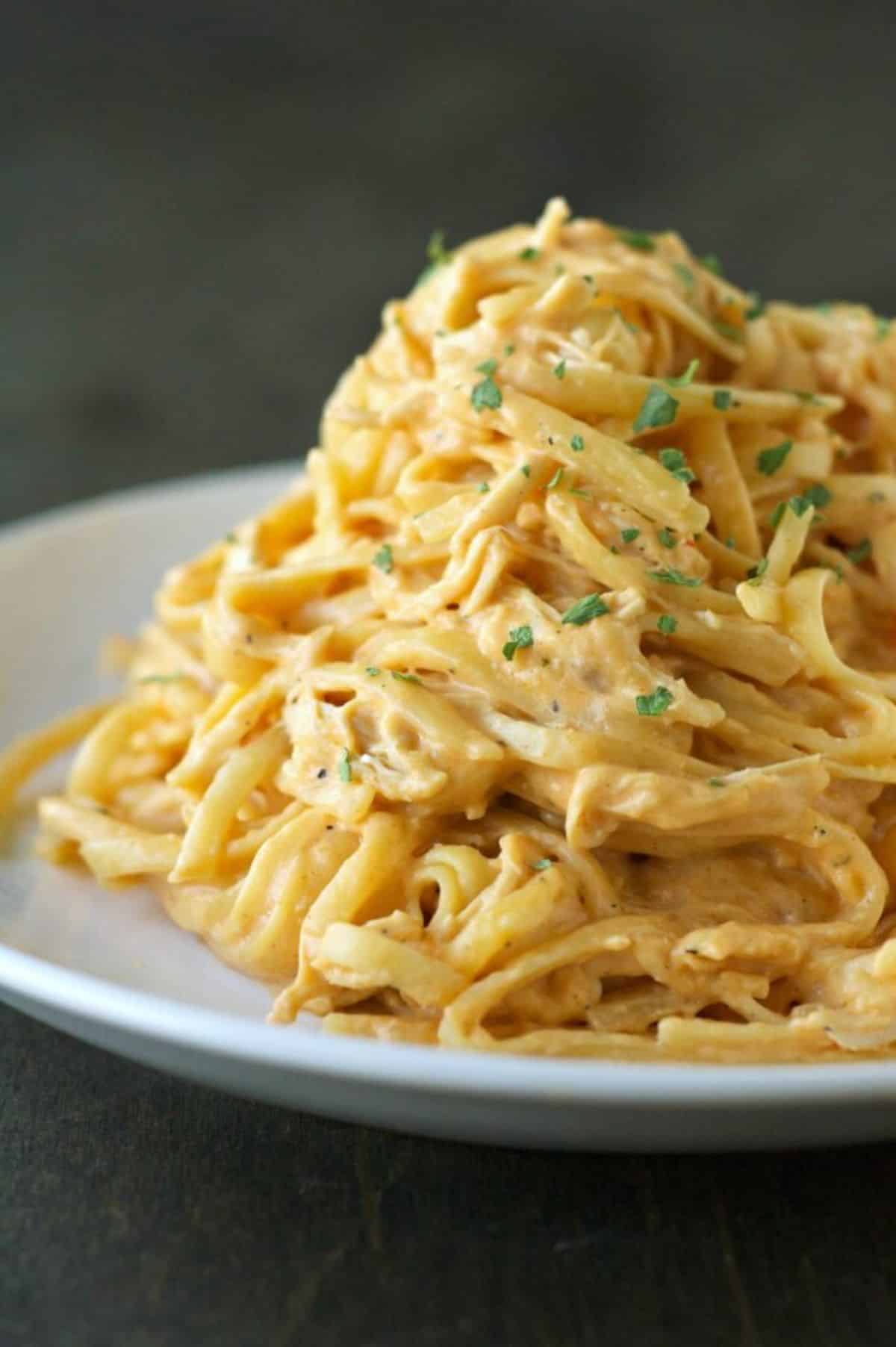 A pile of slow cooker cheesy buffalo chicken pasta on a white plate.
